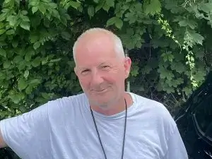 Brian-Stern_03_BRM-300x225 Photo of Brian Stern standing in front of a green bush.